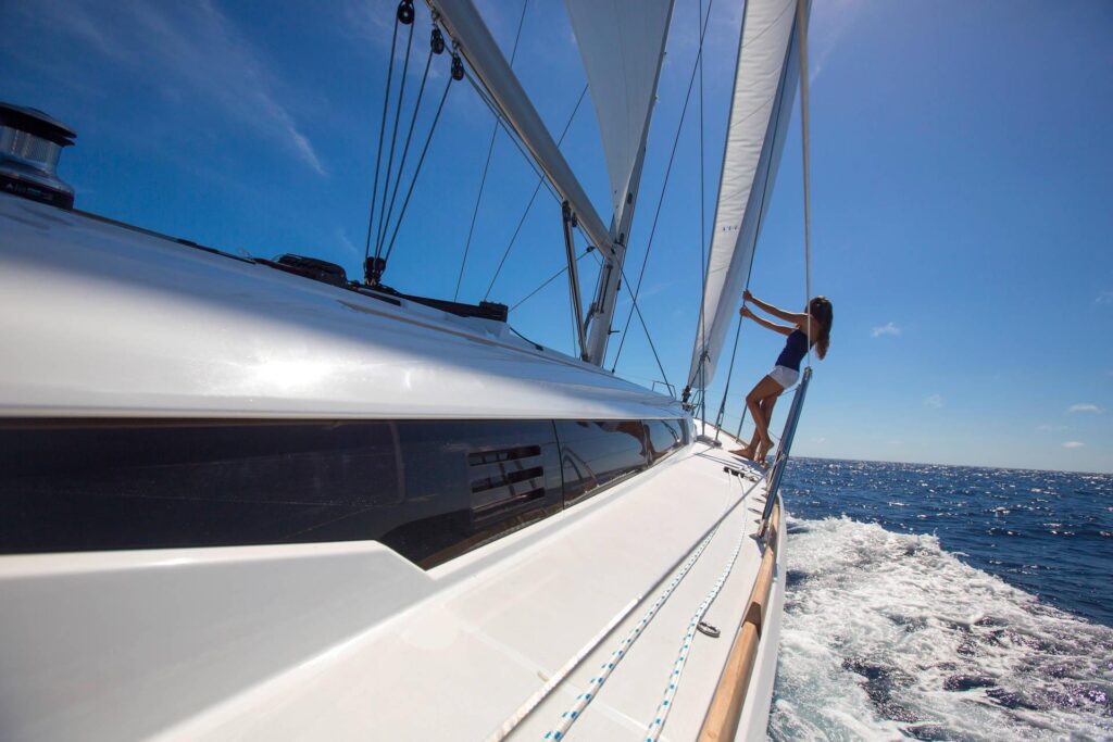 Woman holding onto the ropes of a Jeanneau Sun Odyssey 479, enjoying the waters.