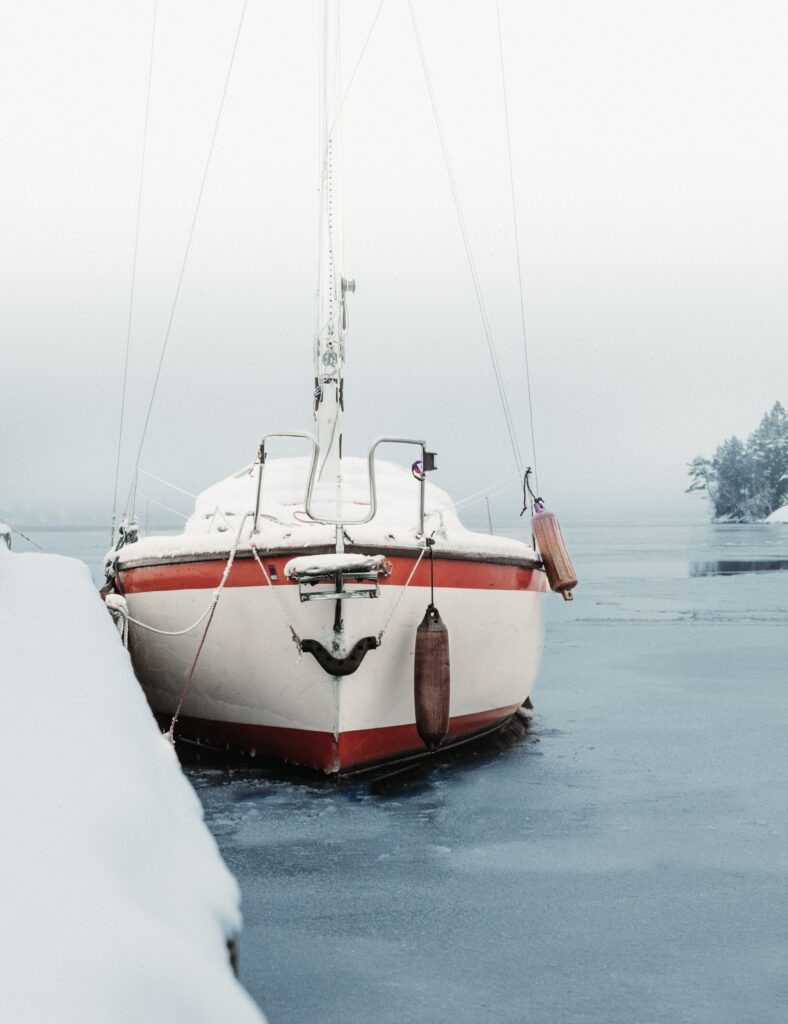 Vertical shot of a boat covered in snow under a cloudy sky during winter
