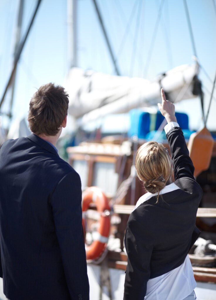 Young business people looking at a yacht together at the marina.