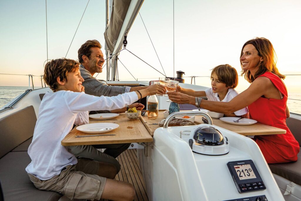 Two parents and two kids having a toast at the outdoor table of a jeanneau sun odyssey 410.