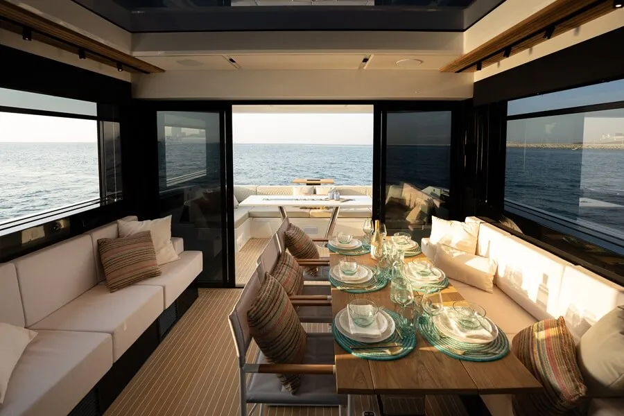 Helm interior dining table and sofas with access to deck. With the aft beach club open at water level, guest enjoy sea access.